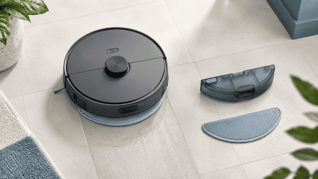Robot vacuum with detachable mop and cleaning pads on tiled floor.